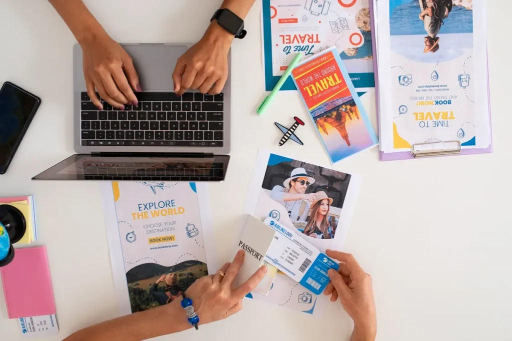 Mesa com materiais promocionais de viagem, incluindo laptop, folhetos, passaporte e passagens aéreas, representando o planejamento de viagens em uma agência de turismo