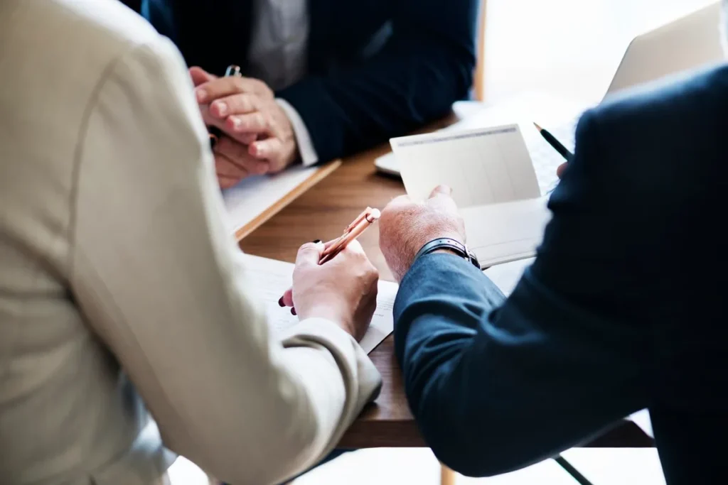 Profissionais em uma mesa de reunião discutindo documentos e estratégias de negócios com foco em planejamento e tomada de decisão.