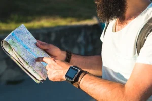 Turista segurando um mapa detalhado enquanto aponta uma localização, representando planejamento de viagem e exploração