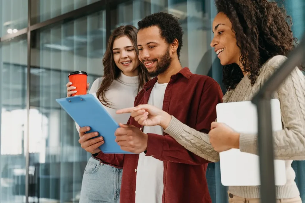 Grupo de colegas de trabalho discutindo ideias em equipe, segurando um tablet e apontando para informações relevantes sobre engajamento.