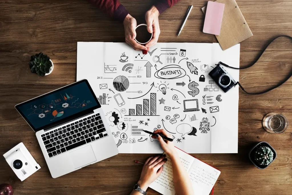 Mãos colaborando em um plano estratégico de marketing e vendas, com elementos visuais de gráficos, diagramas e tecnologia.