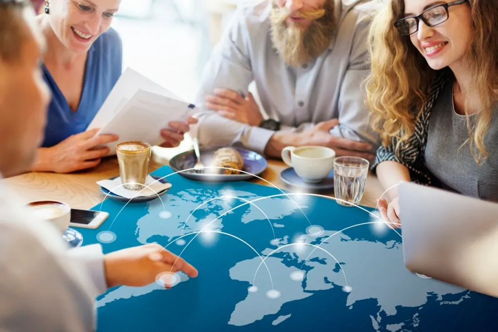 Profissionais discutindo estratégias globais ao redor de uma mesa com um mapa-múndi projetado, simbolizando marketing internacional