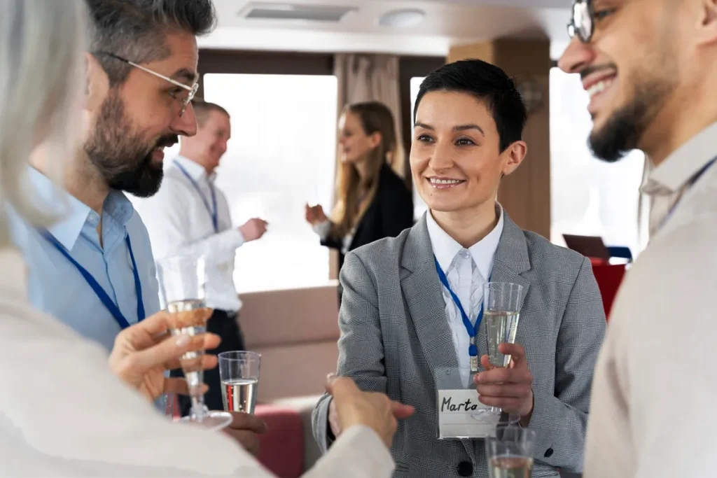 Pessoas conversando em um evento corporativo com crachás e taças de bebida