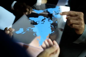 Mãos segurando uma placa com o mapa-múndi azul, representando estratégias de marketing internacional e expansão global.