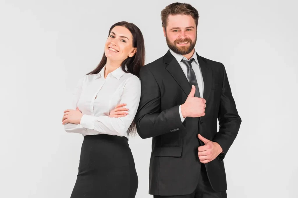 Executivos sorrindo, com mulher de braço cruzado e homem fazendo sinal de positivo, ambos vestindo trajes formais