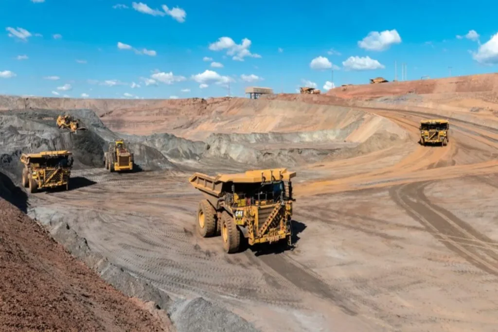 Vários caminhões de mineração amarelos em uma mina a céu aberto, transportando material extraído.