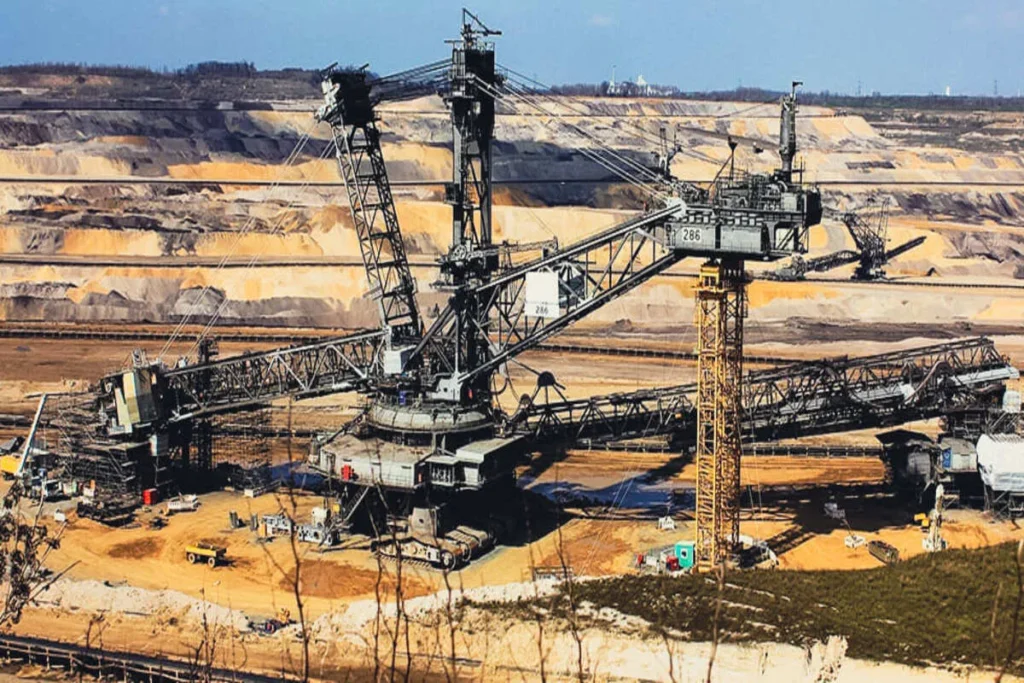 Escavadeira gigante de roda de caçambas em uma vasta mina a céu aberto, representando o setor de mineração.