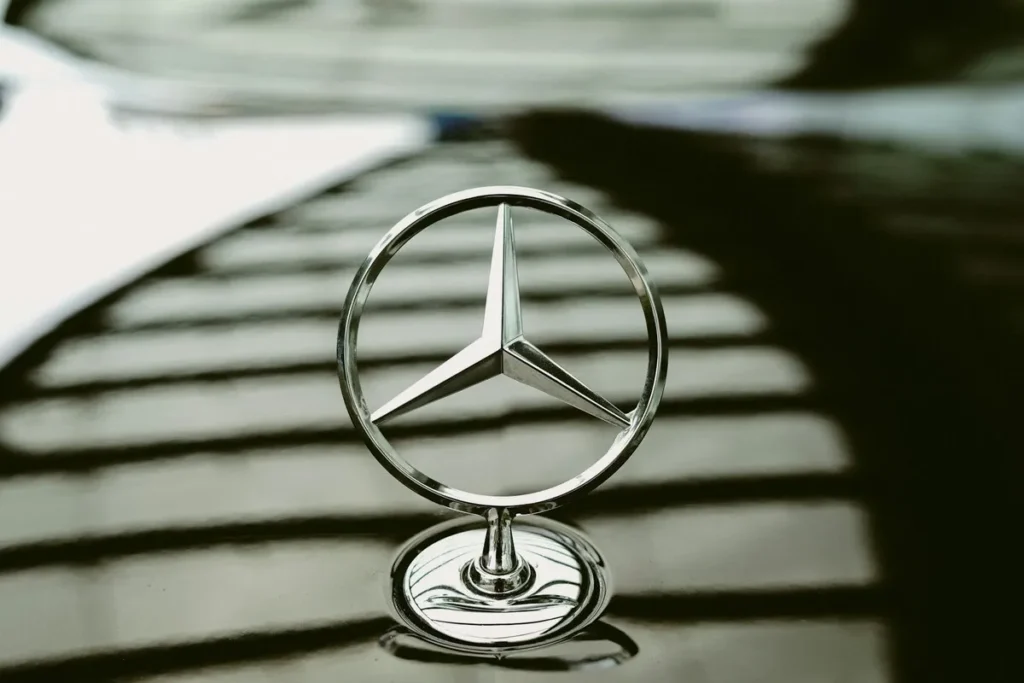 Logotipo da Mercedes-Benz, uma das mais conhecidas multinacionais do mundo, no capô de um carro.