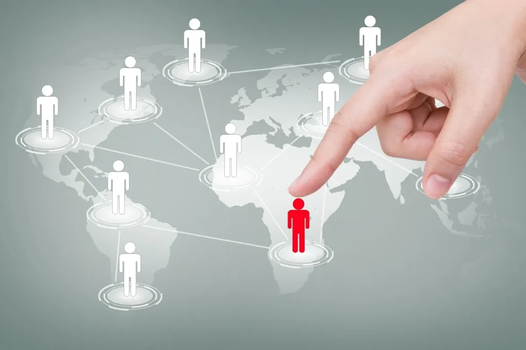 Imagem ilustrando uma rede global com figuras humanas conectadas por linhas, onde uma pessoa em destaque, representada em vermelho, está sendo selecionada em meio aos outros pontos de conexão, simbolizando a escolha de talento em um contexto multinacional