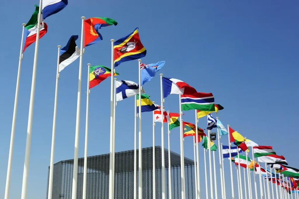 Bandeiras de vários países hasteadas, simbolizando o alcance global e a presença de multinacionais.