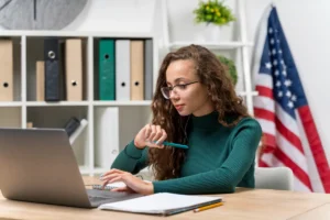 Mulher estudando inglês no computador com bandeira dos EUA ao fundo
