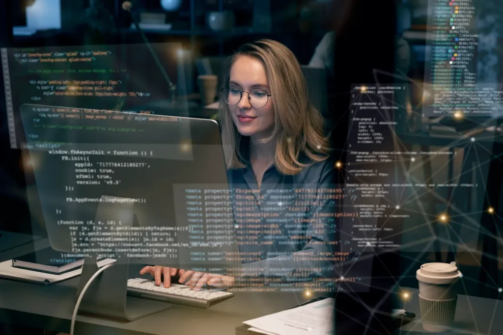 Mulher programadora usando óculos, digitando em um computador com código-fonte e redes de dados sobrepostos na tela, em um ambiente de escritório moderno e iluminado.