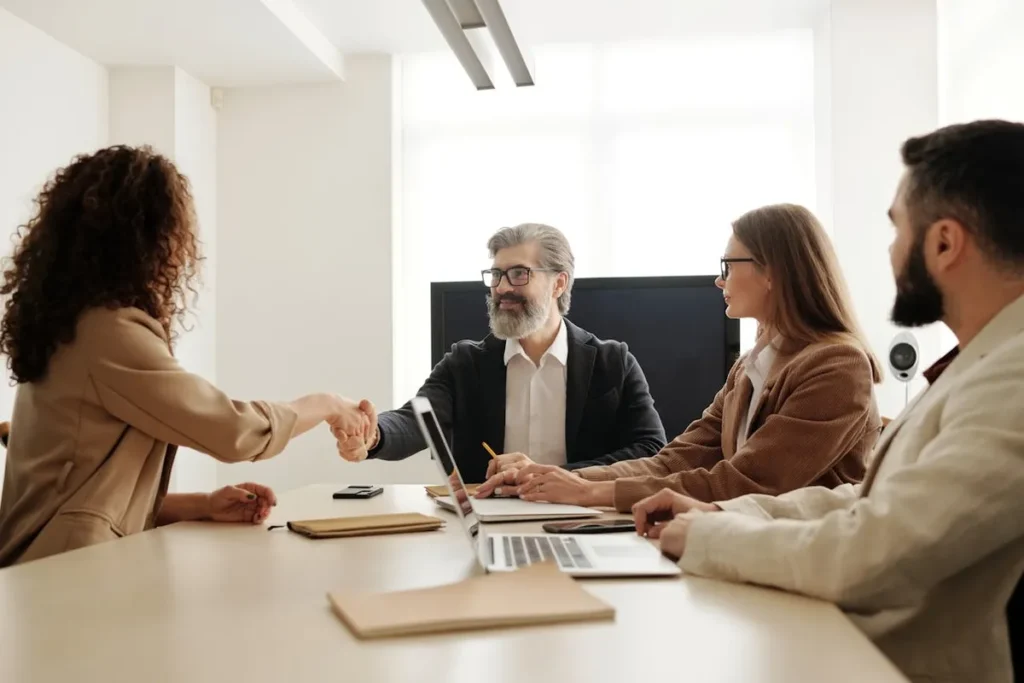Reunião de Recursos Humanos: Mulher e homem apertando as mãos em uma mesa de reunião.