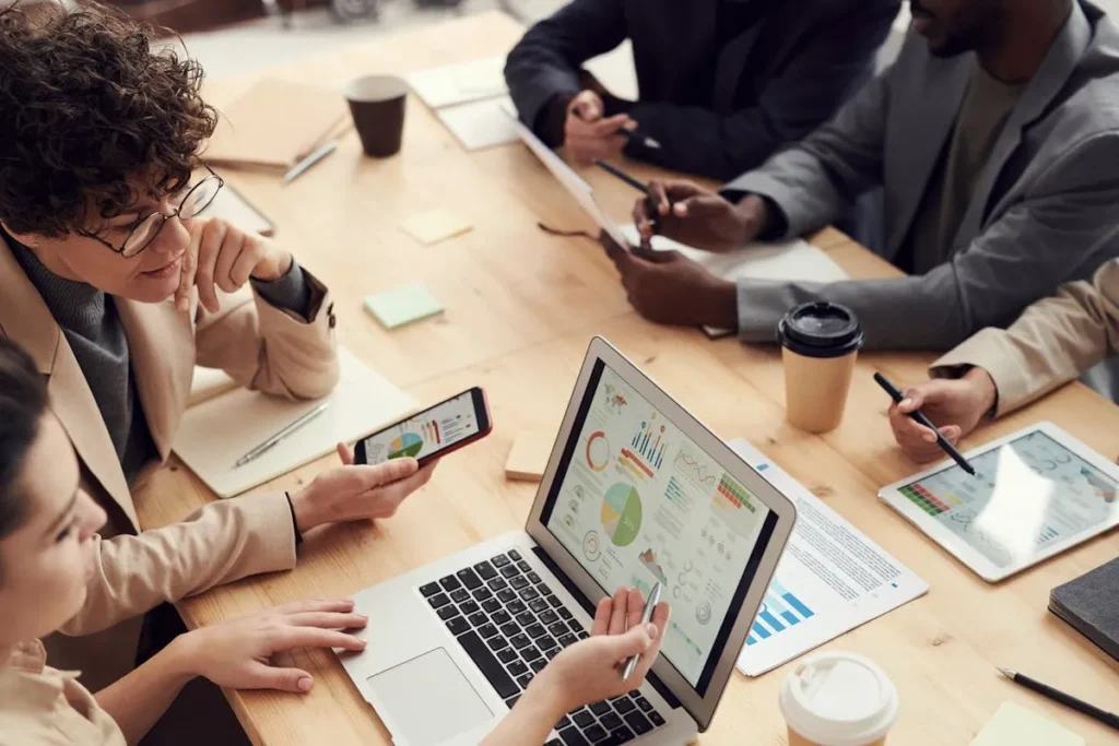 Equipe de recursos humanos em reunião analisando dados e gráficos em laptop.