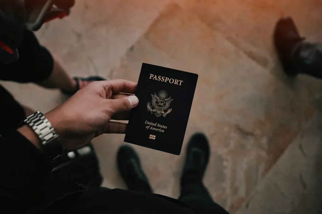 Pessoa segurando um passaporte dos Estados Unidos com fundo desfocado.