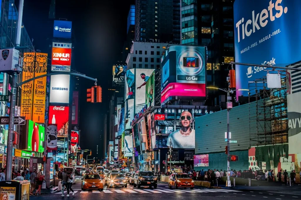 Vista noturna da Times Square em Nova York com painéis luminosos, carros e pedestres