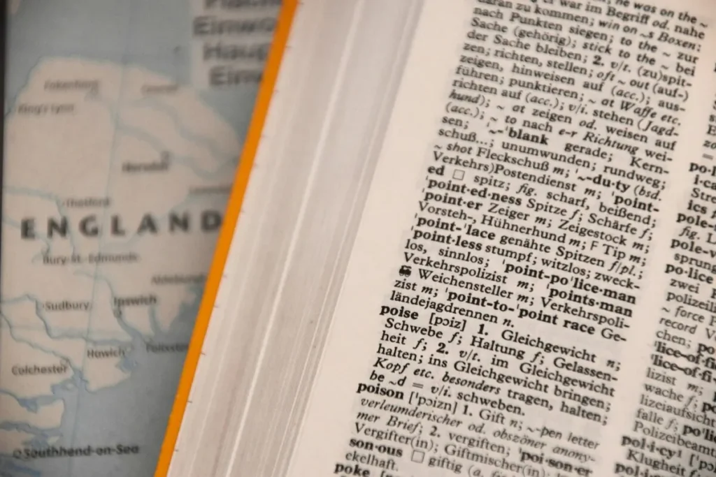 Imagem de um dicionário inglês-alemão aberto ao lado de um mapa com destaque para "England"