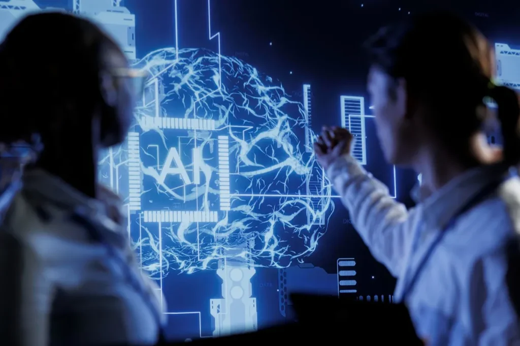 Duas cientistas de dados discutindo um projeto de machine learning com ilustração de cérebro de IA na tela.