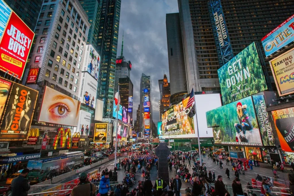 Multidão de pessoas e letreiros iluminados na Times Square, em Nova York.