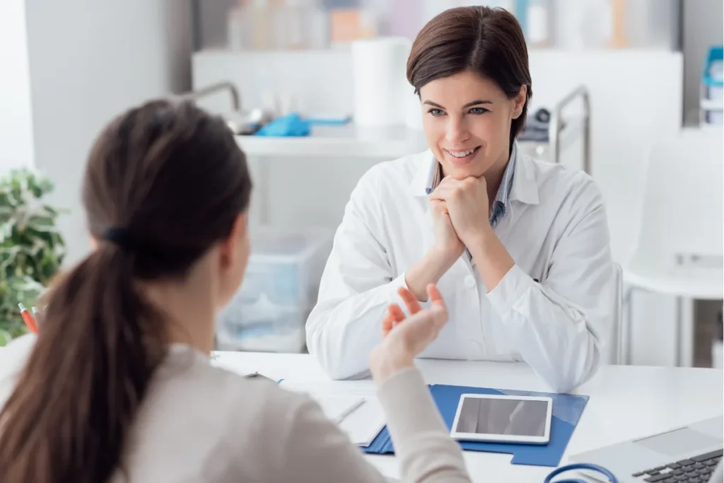 Médica sorrindo enquanto conversa com paciente durante atendimento clínico