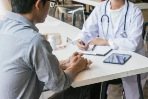 Médico conversando com paciente sentado durante consulta em ambiente hospitalar